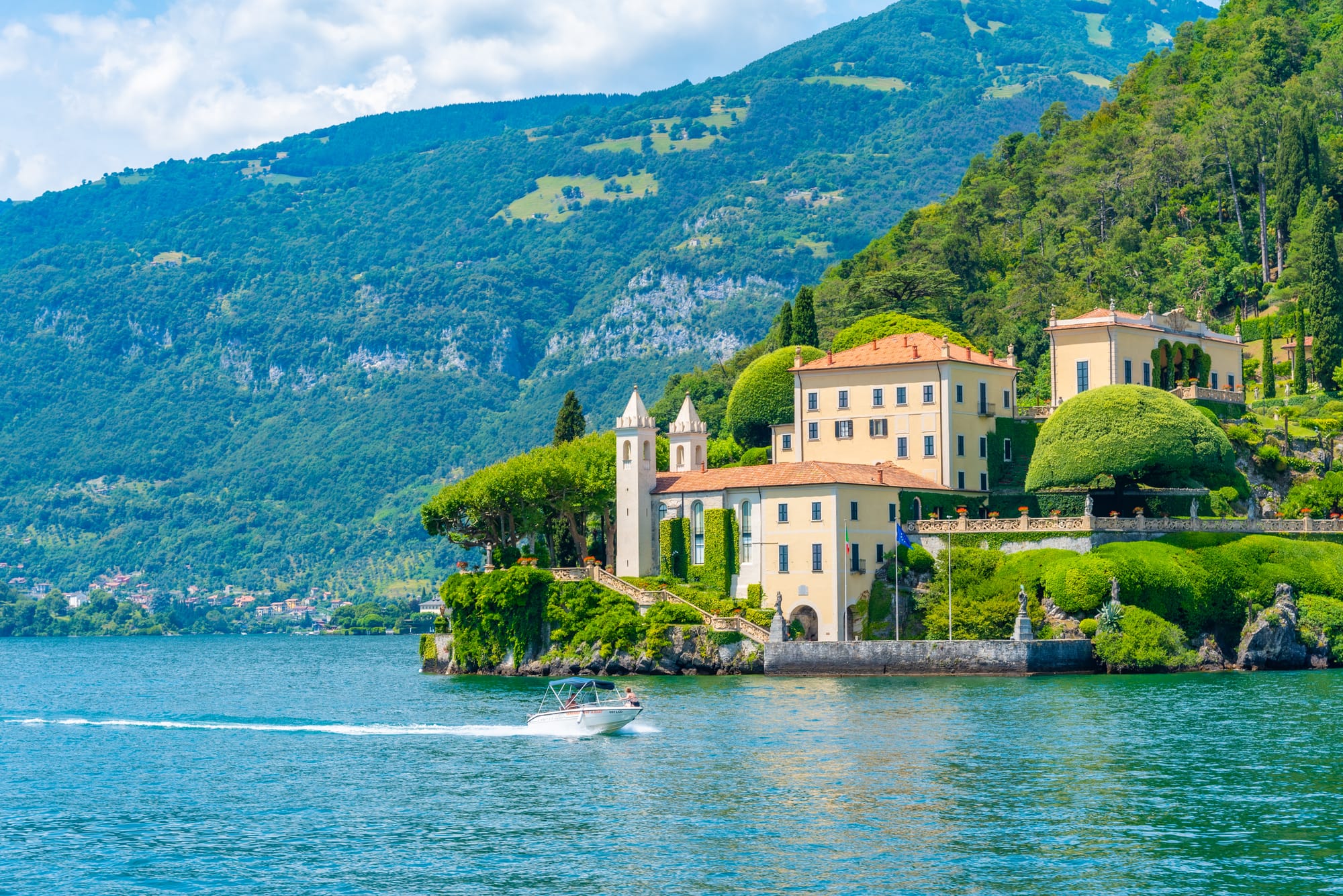 A grand, historic villa on the shores of Lake Como, Italy, viewed from the water. The elegant architecture and lakeside gardens showcase the beauty of famous Lake Como villas like Villa del Balbianello.