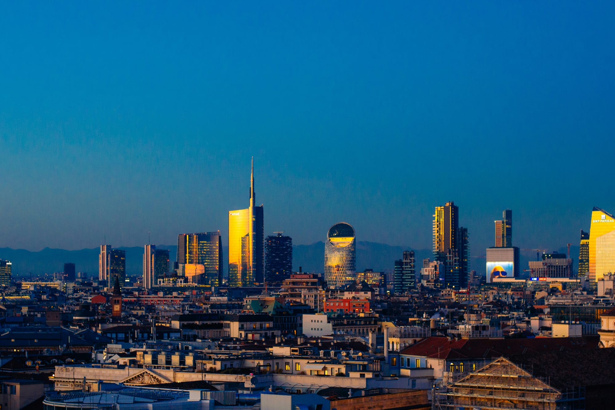 The modern Milan skyline at sunrise, featuring the skyscrapers of the Porta Nuova and Isola districts illuminated by the morning light, a symbol of Milan's blend of history and modernity.