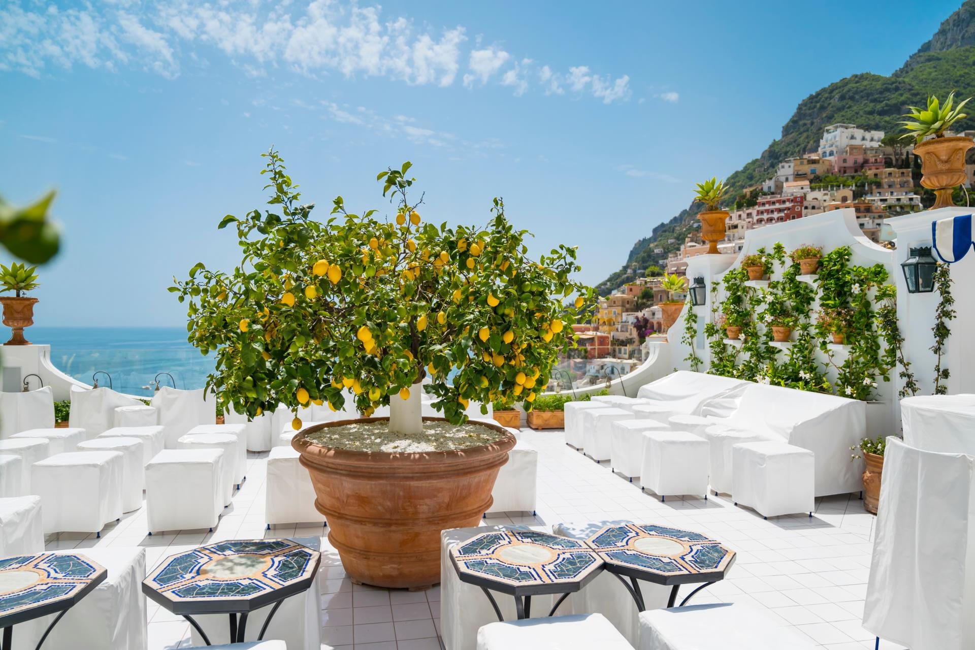 A vibrant lemon tree with ripe yellow lemons on a traditional Mediterranean balcony in Positano with a sea view.