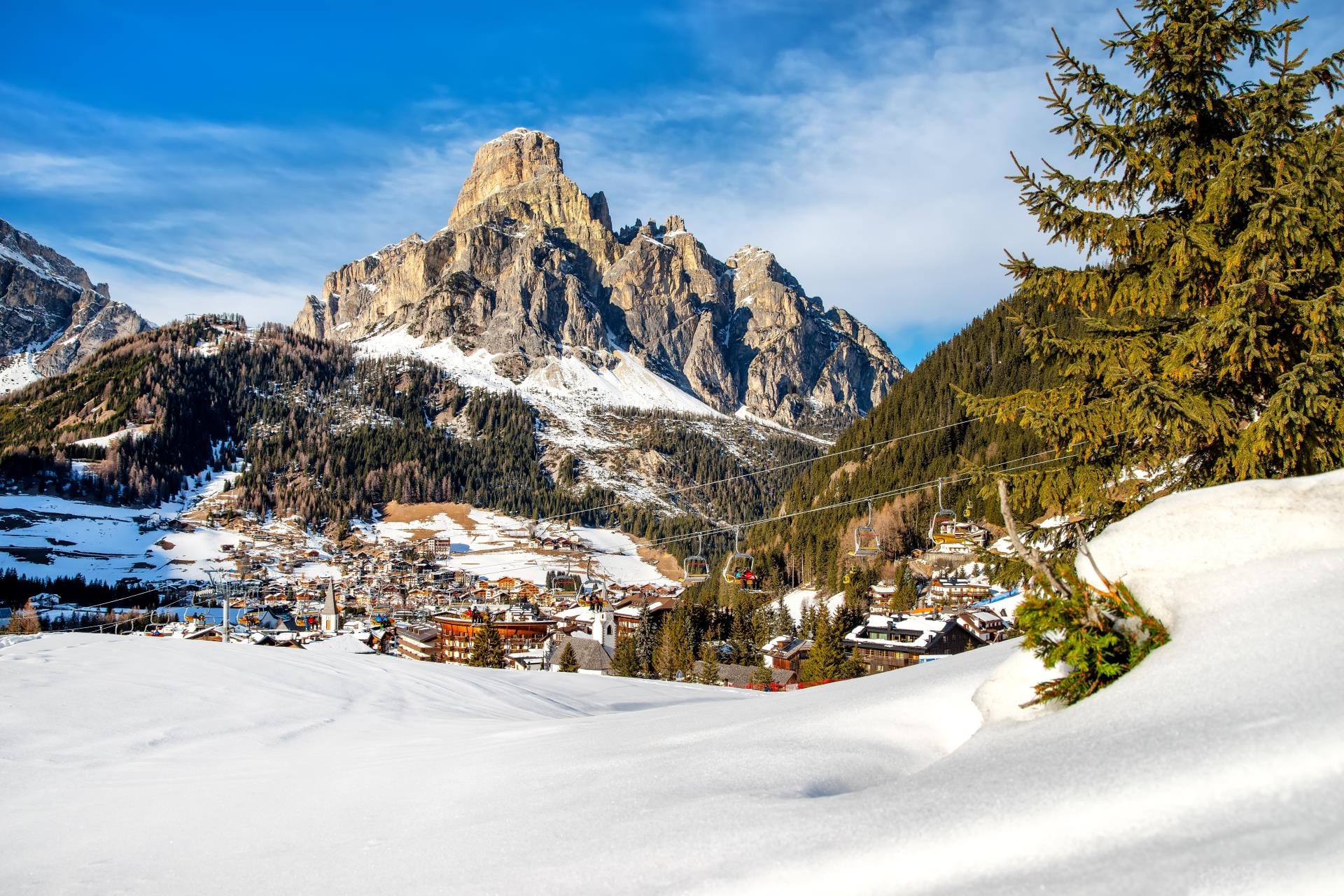 The luxury ski resort village of Corvara on a sun-drenched day in Alta Badia, Dolomites.