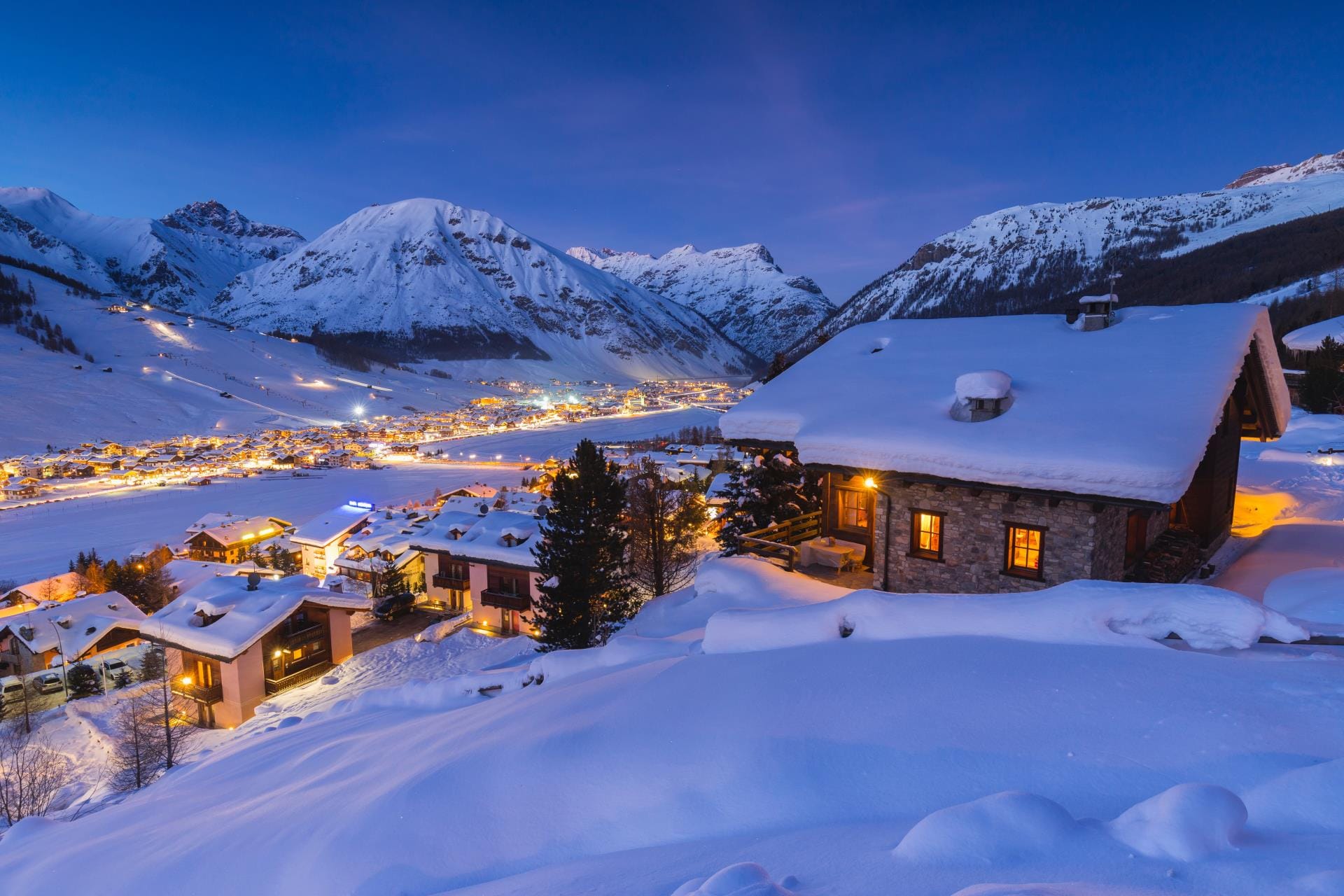Evening lights illuminating the snow-covered streets and traditional buildings of Livigno, Italy.
