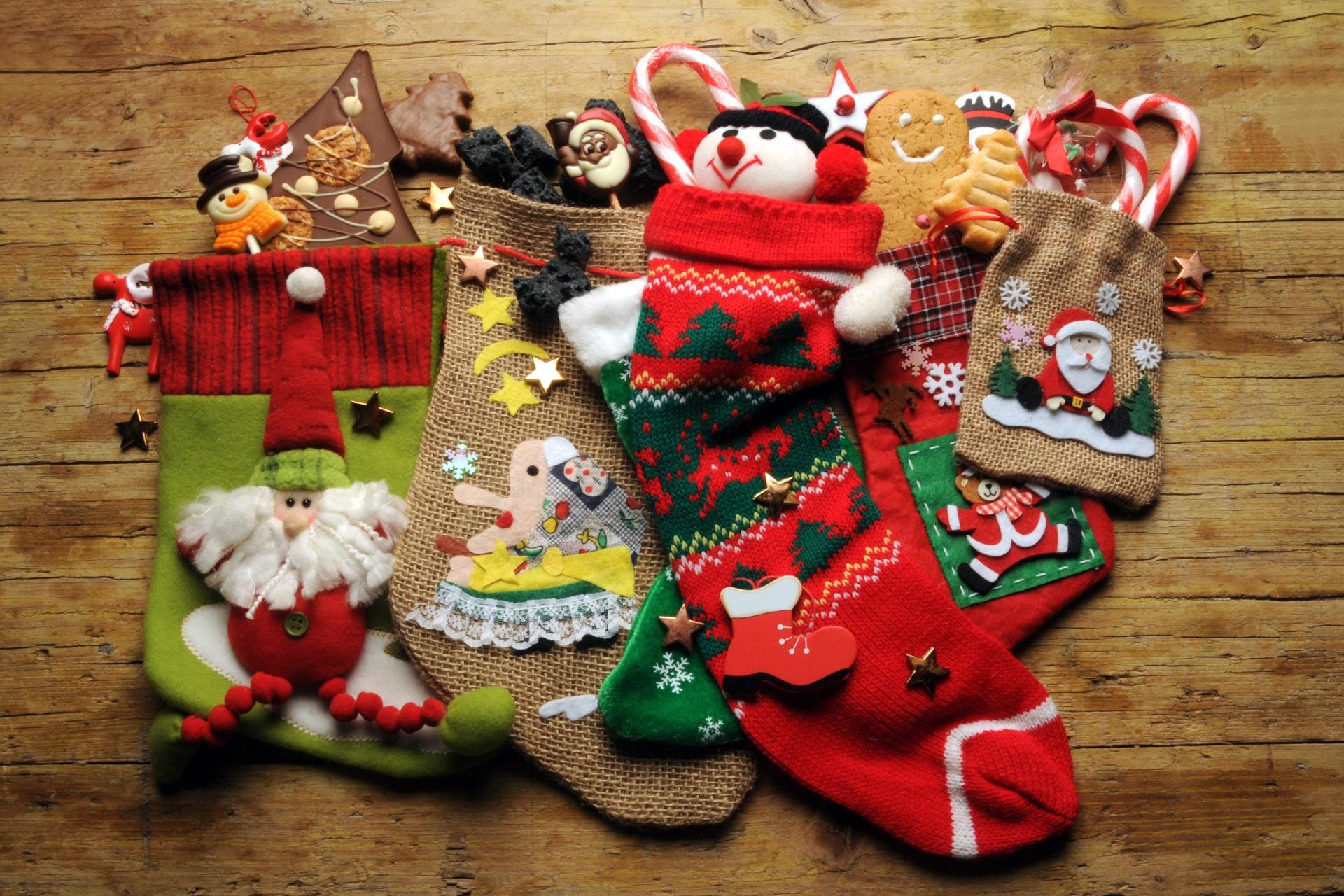 Traditional Italian Befana stockings hanging by a fireplace filled with artisanal chocolates, candies, and sweet coal.