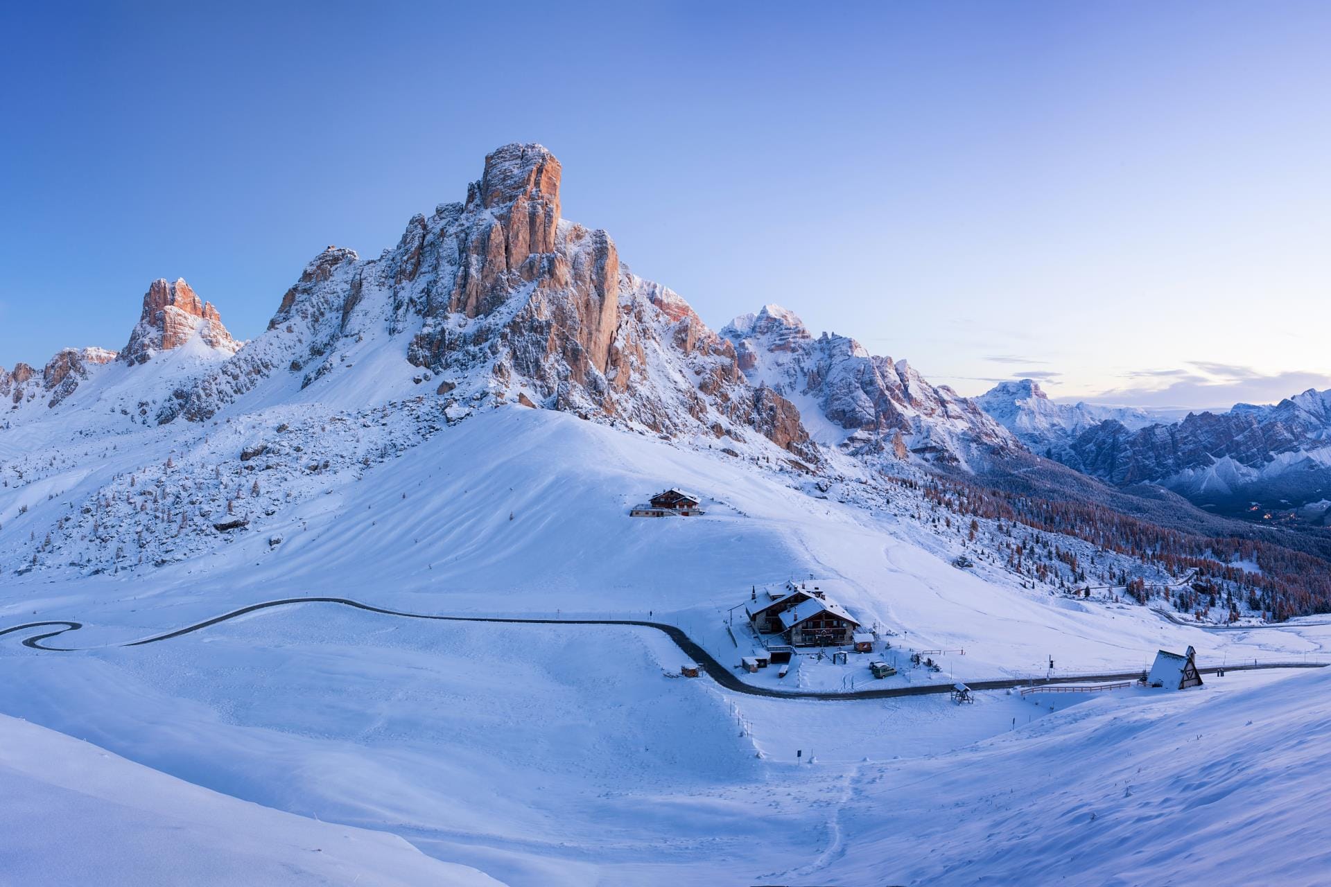 Drone perspective of the snow-covered Passo Giau mountain pass and dramatic peaks in the Dolomites during winter.