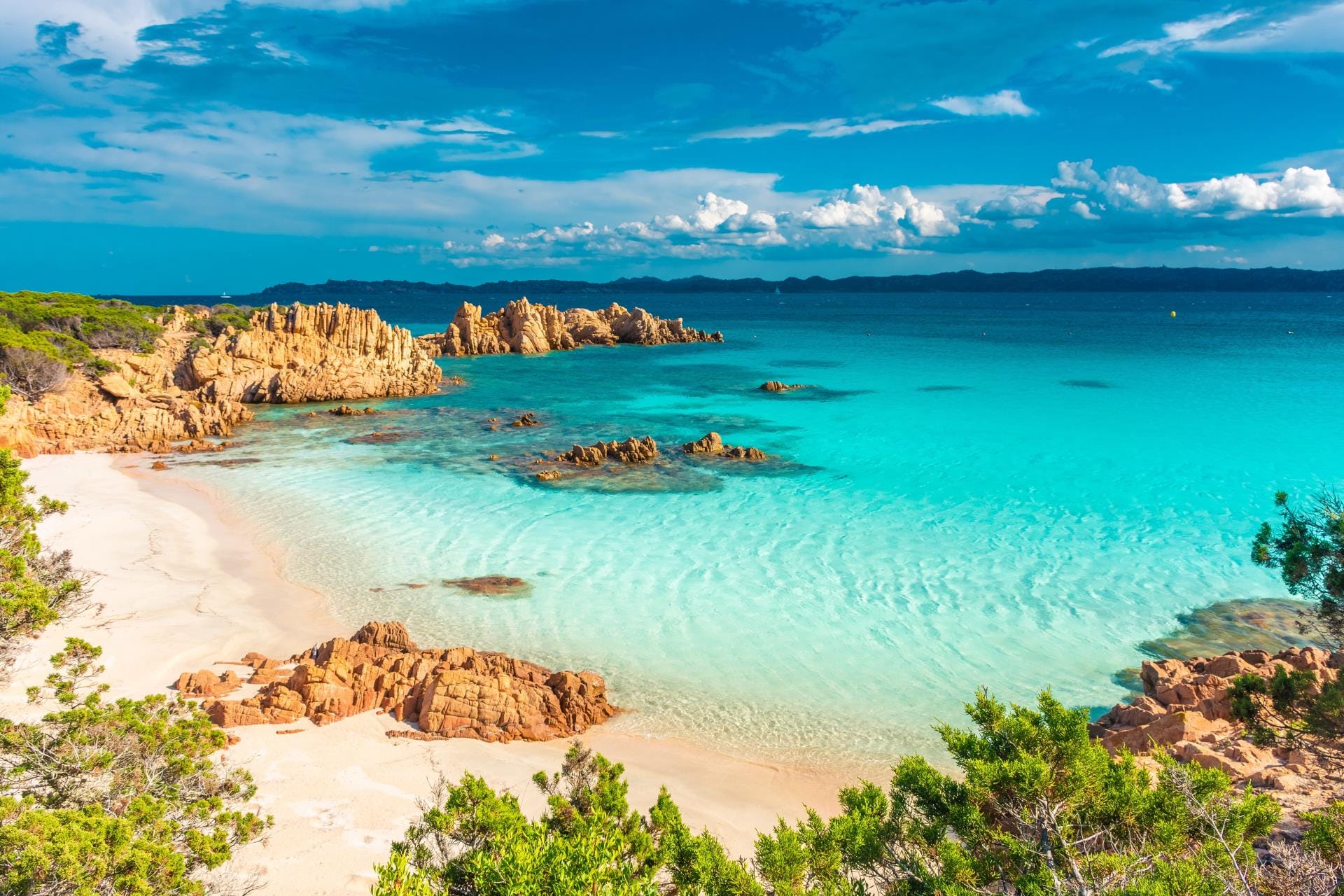 Crystalline turquoise water lapping against the unique pink sand beach on Budelli Island in Sardinia.
