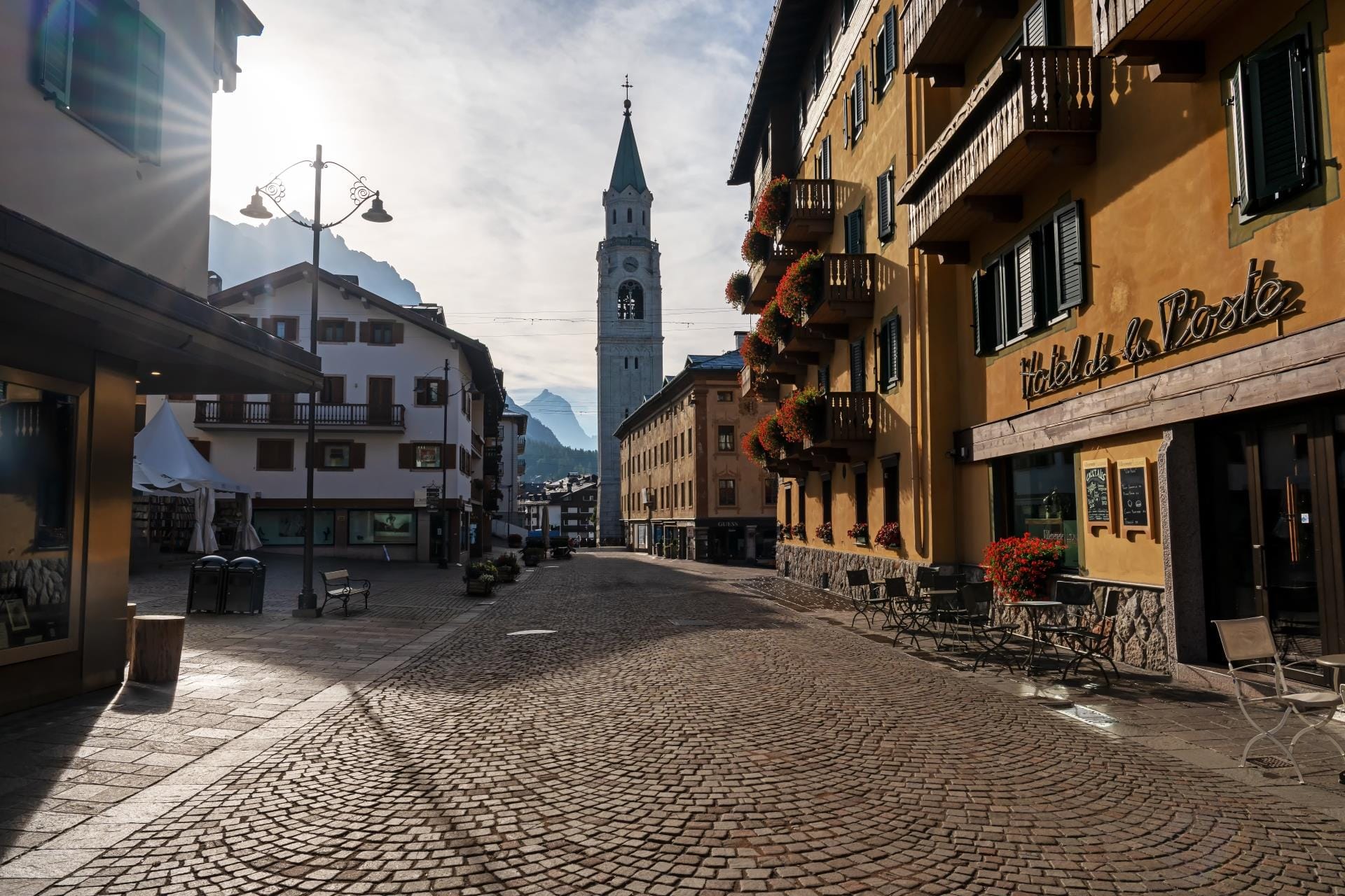 Pedestrian street of Corso Italia in Cortina d'Ampezzo featuring the historic bell tower of the Basilica Minore dei Santi Filippo e Giacomo.