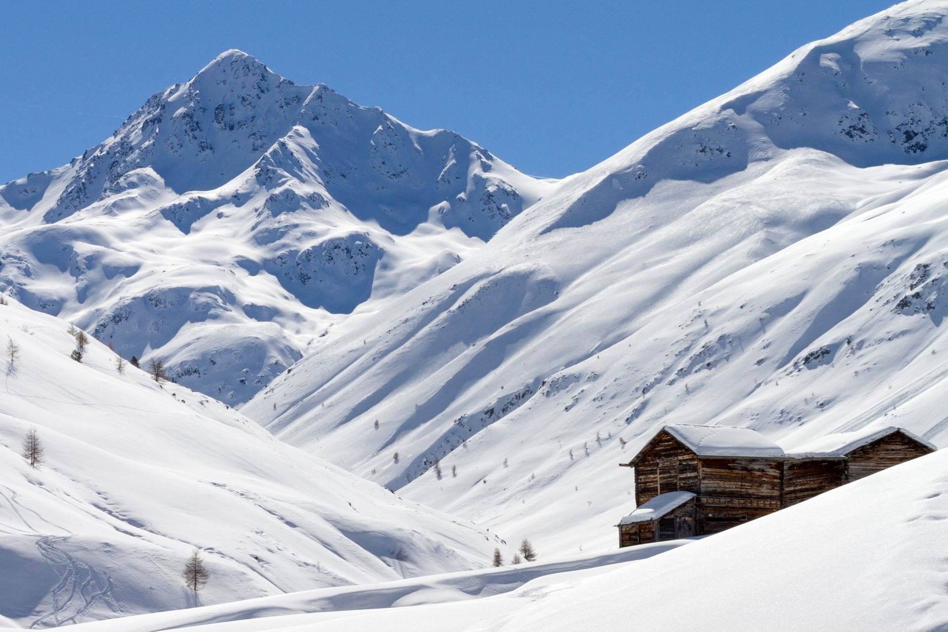 Panoramic landscape of the snow-covered Vallaccia valley in Livigno surrounded by pristine white alpine peaks.