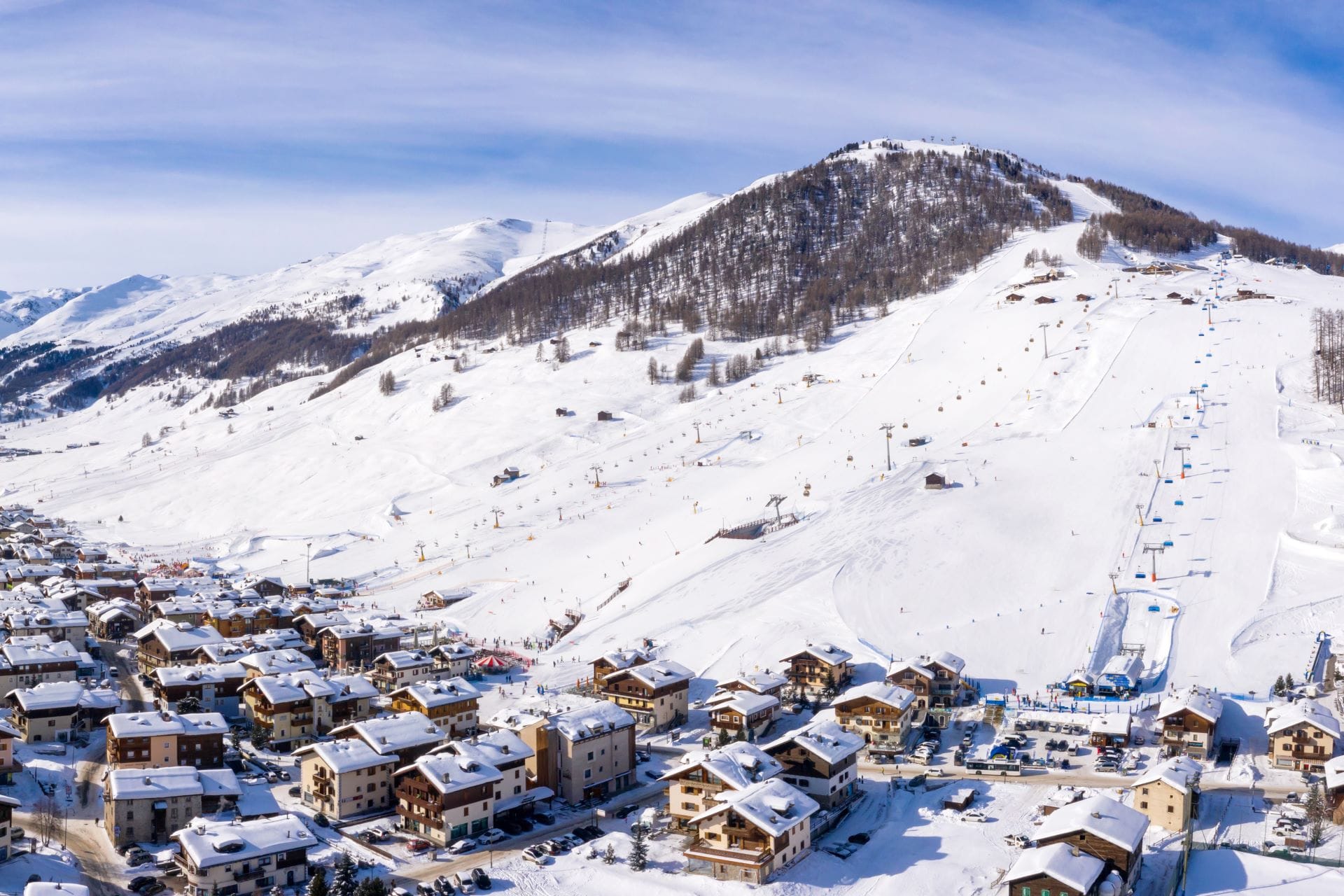 Aerial drone view of Livigno village in Northern Italy showing the groomed ski slopes of the Carosello 3000 mountain area.
