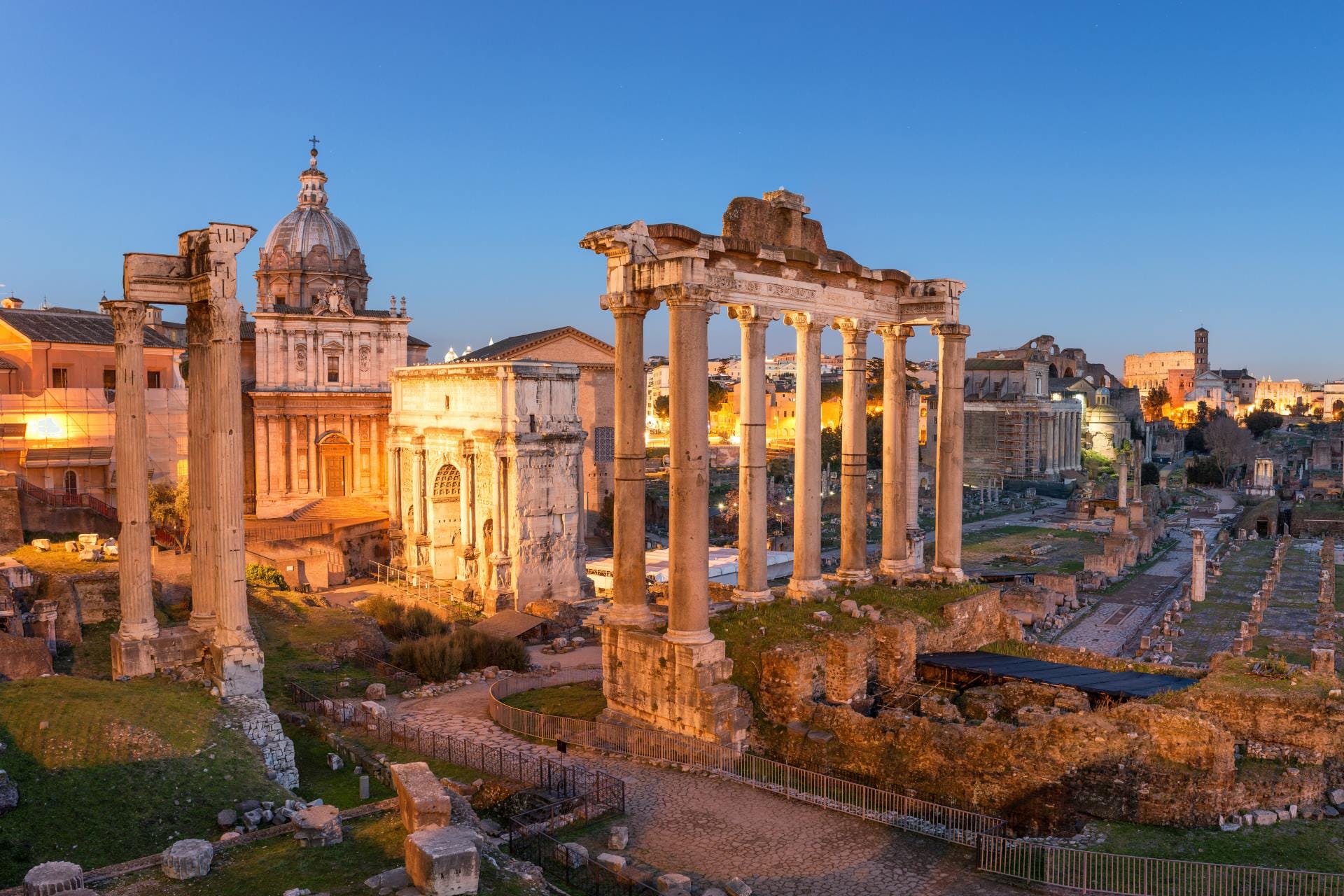 Golden hour sunset light hitting the ancient ruins of the Roman Forum and Palatine Hill.