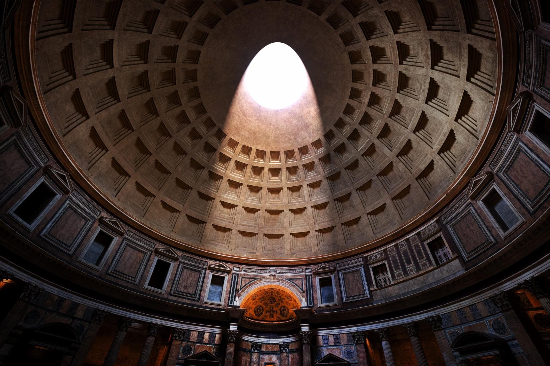 Interior of the Pantheon in Rome showing the concrete dome and light streaming through the oculus.