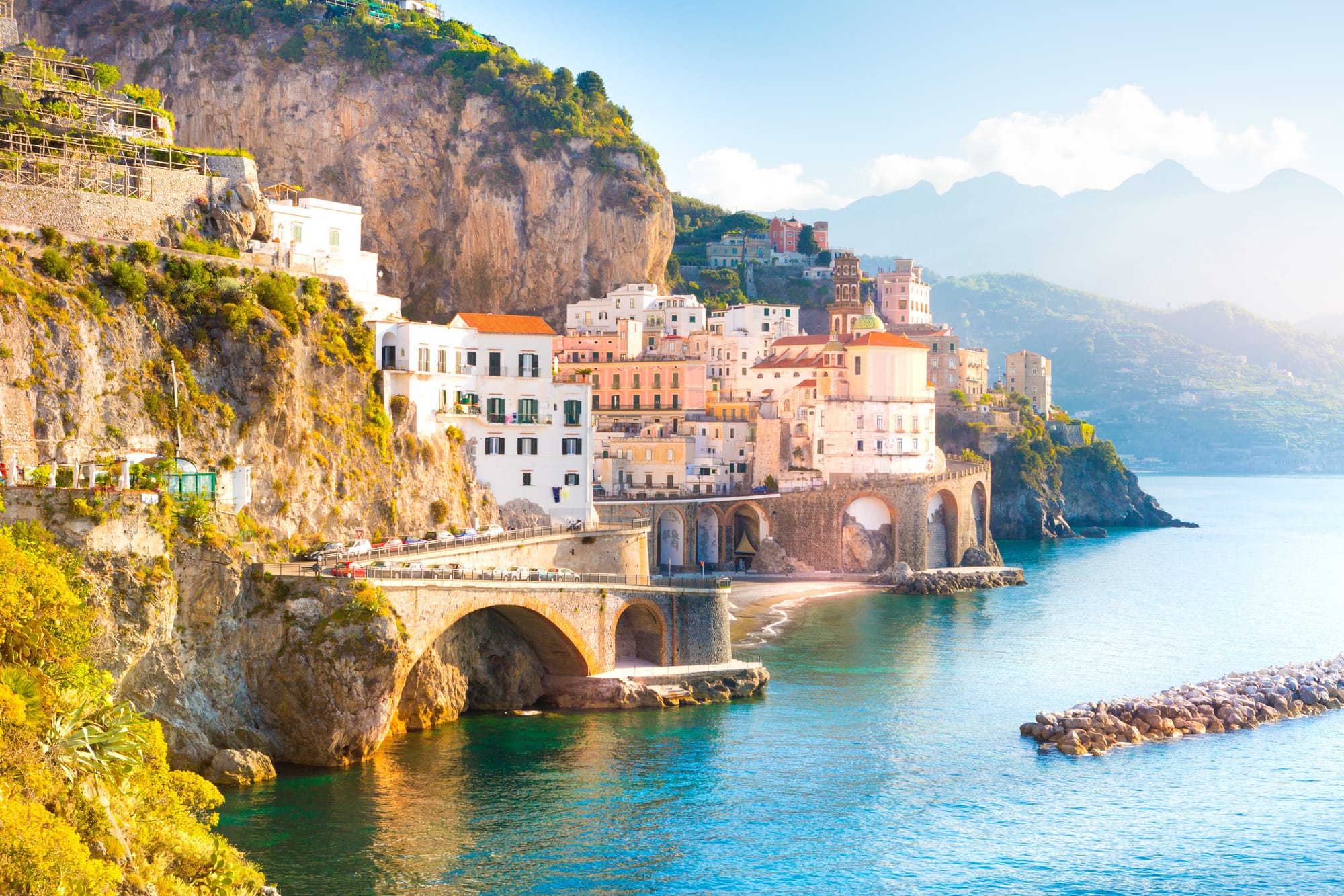 Colorful buildings of the town of Amalfi, Italy, tumbling down a cliff to the Mediterranean Sea on a bright morning, a key destination on the Amalfi Coast.
